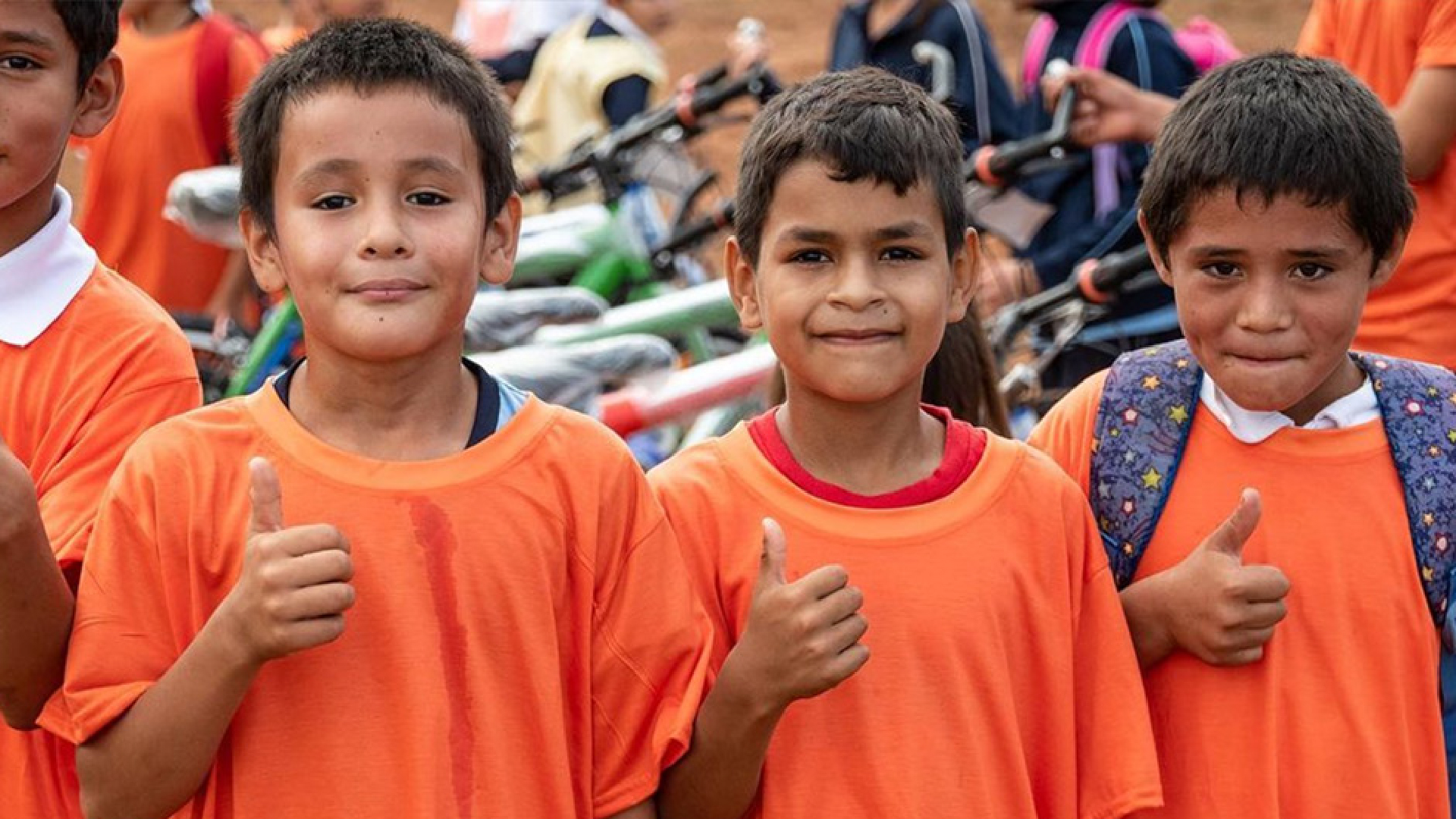 Tres niños sonriendo con el pulgar hacia arriba