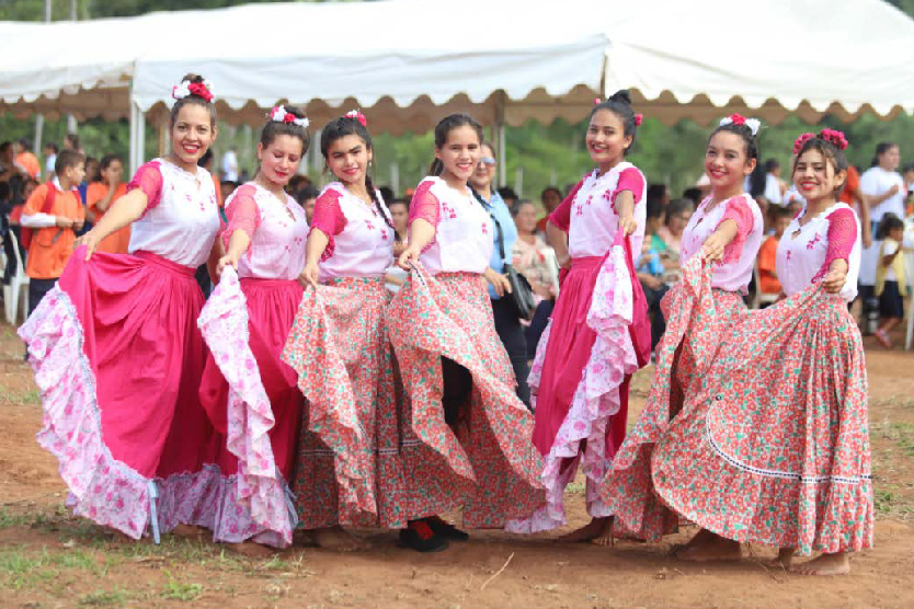 Siete chicas sonriendo con vestidos coloridos de la cultura del Paraguay